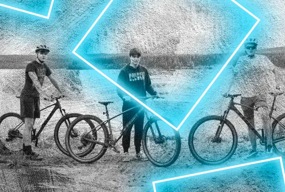 Cyclists holding mountain bikes for a picture